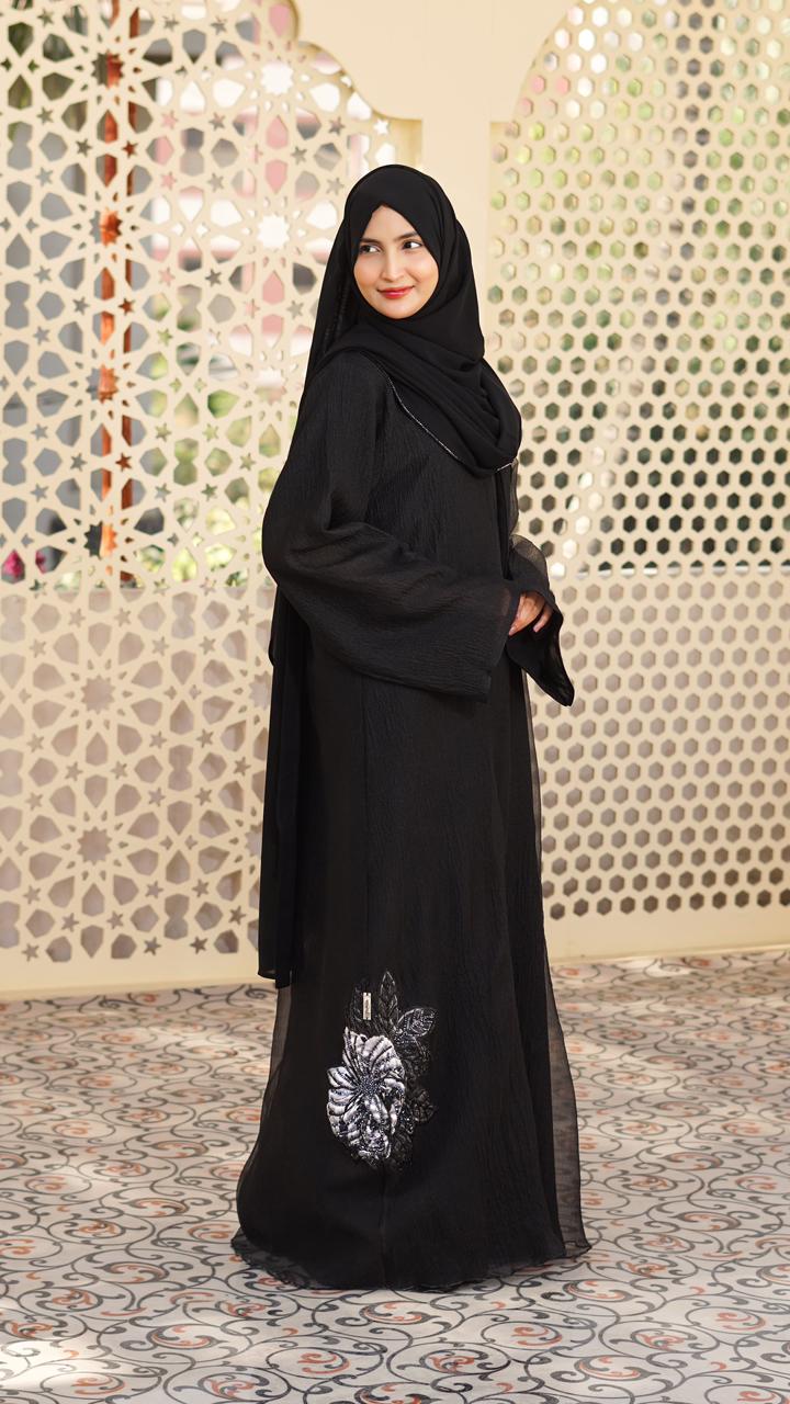 A luxurious black organza abaya with delicate floral embroidery, wide sleeves, and a matching inner for an elegant, refined look.