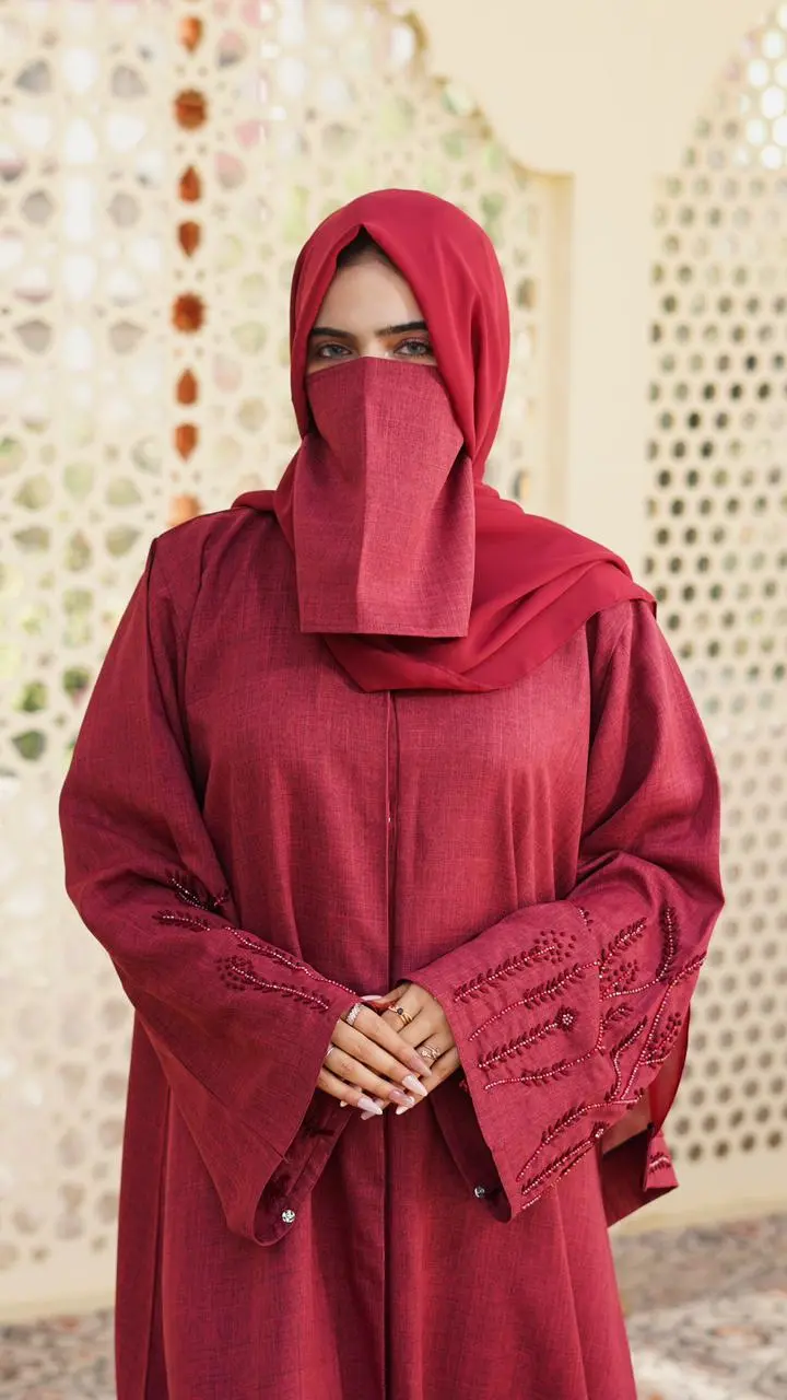 A maroon abaya made from soft, textured linen fabric, featuring elegant embroidery on the sleeves and a modest, flowing silhouette. - Image 2