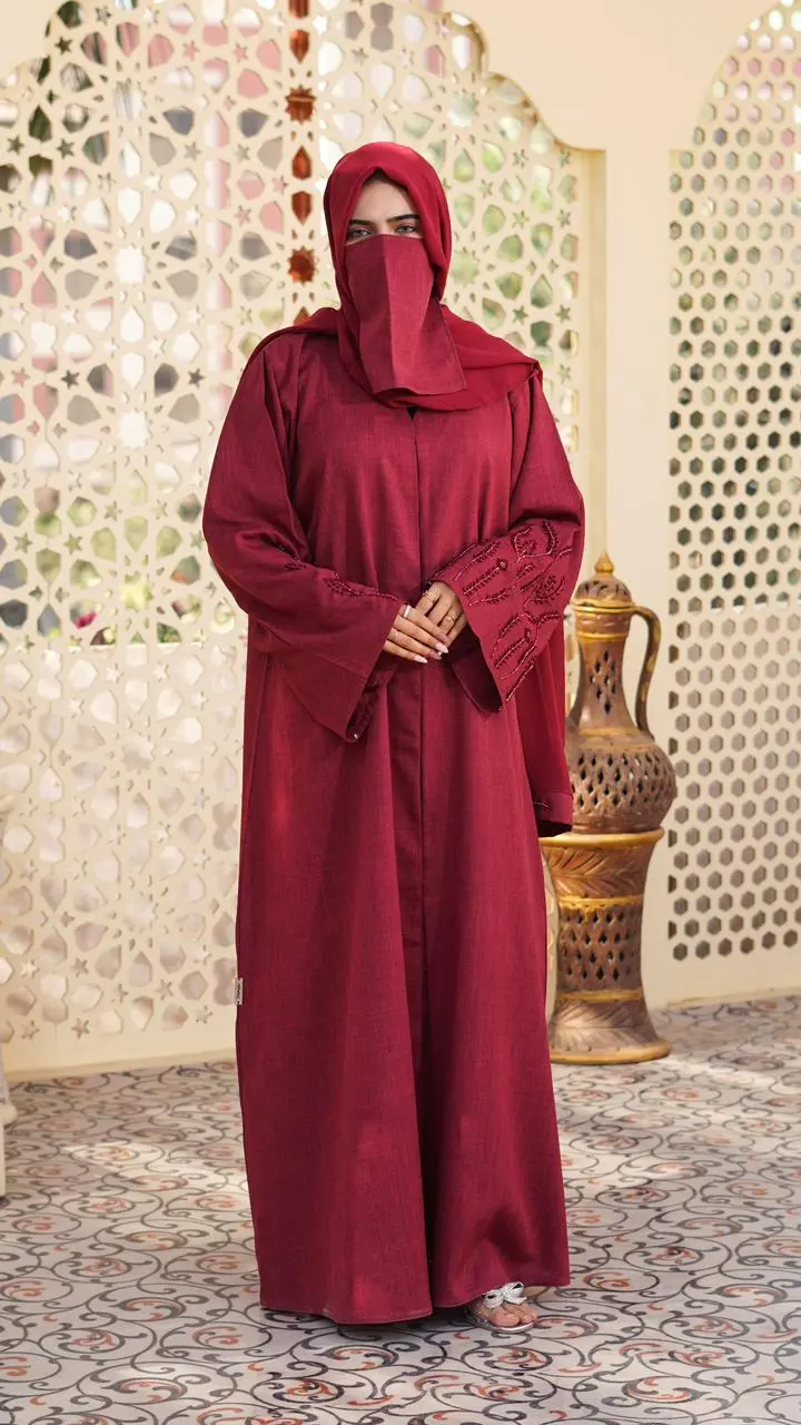 A maroon abaya made from soft, textured linen fabric, featuring elegant embroidery on the sleeves and a modest, flowing silhouette. - Image 3