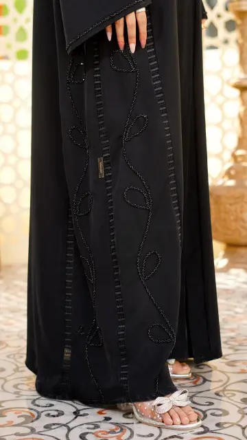 A classic black abaya with a soft, flowing silhouette. Designed with subtle beadwork and delicate embroidery for an elegant, refined finish